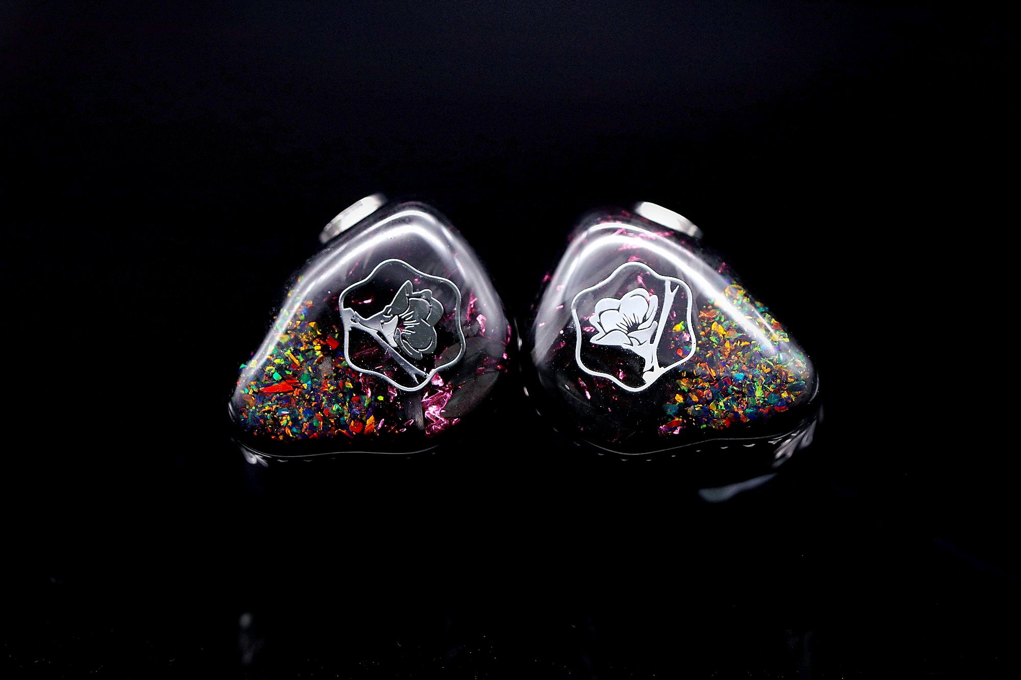 Black Malus faceplates on a black reflective surface with opal fragments and silver flower emblems