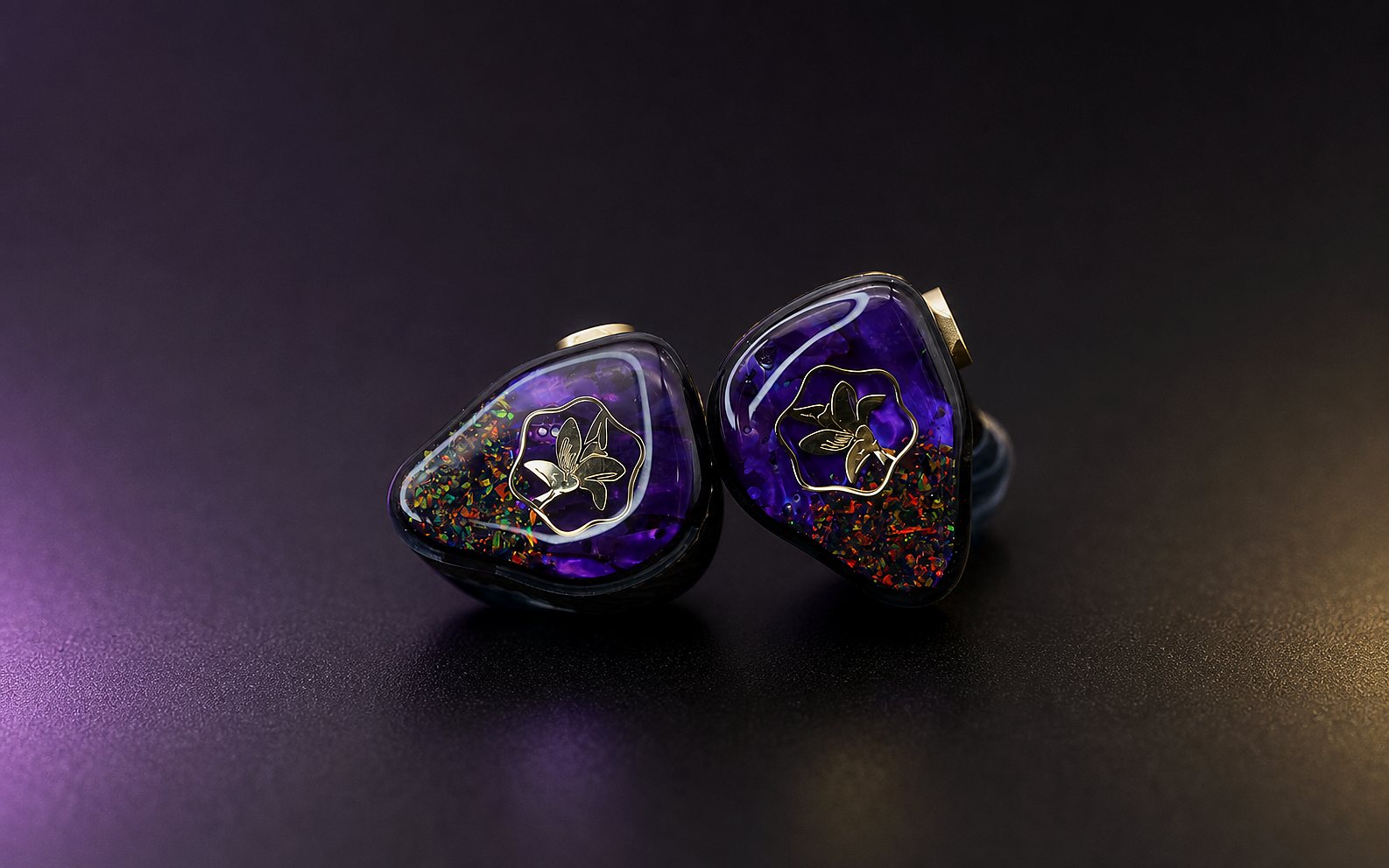 Mokara in-ear monitors with purple opal faceplates on a polished graphite studio surface
